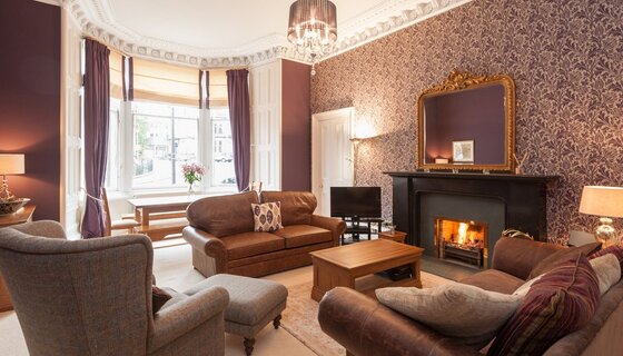 Luxurious holiday homes - A large, spacious room with ample seating on leather sofas, in front of a real open fire. (© The Coates Gardens Residence)