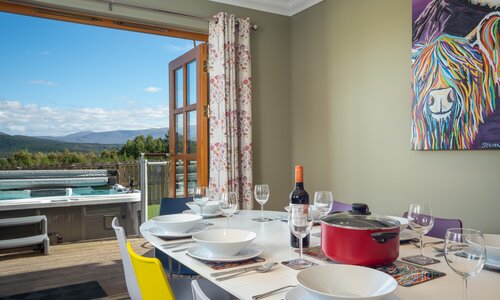 Snowmass Lodge, Aviemore - Dining room with doors opening out to the enclosed garden and hot tub.