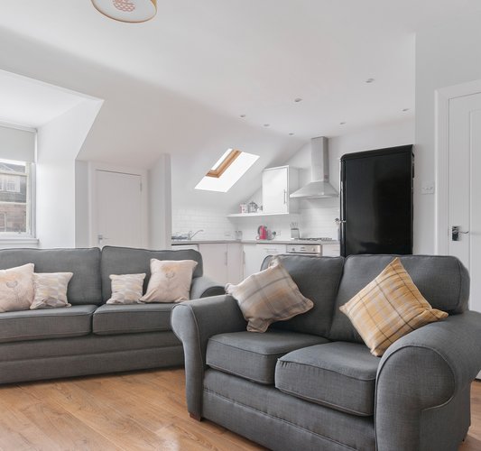 Edinburgh-Flats-self-catering-holiday-apartment-Royal-Mile-High-Street-lounge - Bright spacious Living/Dining/Kitchen open plan area with lovely wooden floors and 2 modern grey sofa and a double sofa bed which sleeps 2 people