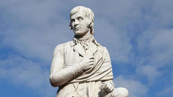 Robert 'Rabbie' Burns Statue in Dumfries - A white statue of Robert 'Rabbie' Burns against a blue sky, located in Dumfries.