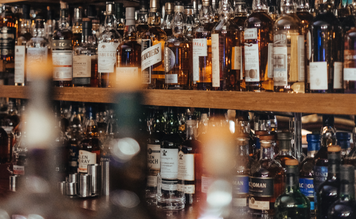 Whisky bottles - Hundreds of golden whisky bottles line a shelf.
