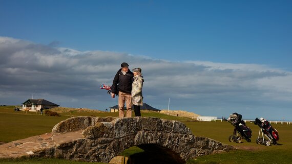 Golf tournaments in Scotland - A couple crossing the famous Swilcan Bridge on the Old Course, St Andrews (© VisitScotland / Peter Dibdin)