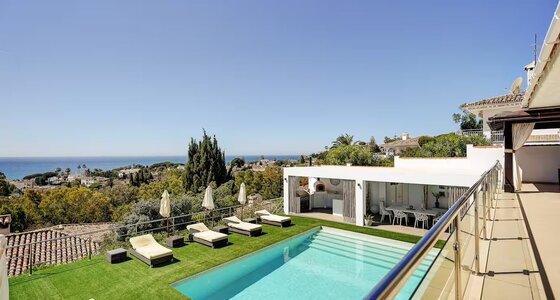 Private Pool with Sea Views - An elevated view of a rectangular swimming pool surrounded by artificial grass and sun loungers, overlooking a coastal landscape. (© Goto Property Management)