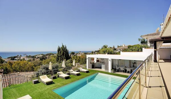 Private Pool with Sea Views - An elevated view of a rectangular swimming pool surrounded by artificial grass and sun loungers, overlooking a coastal landscape. (© Goto Property Management)