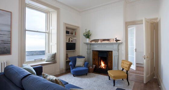 Seaside pet friendly apartment - Living room with open fire and sea views.