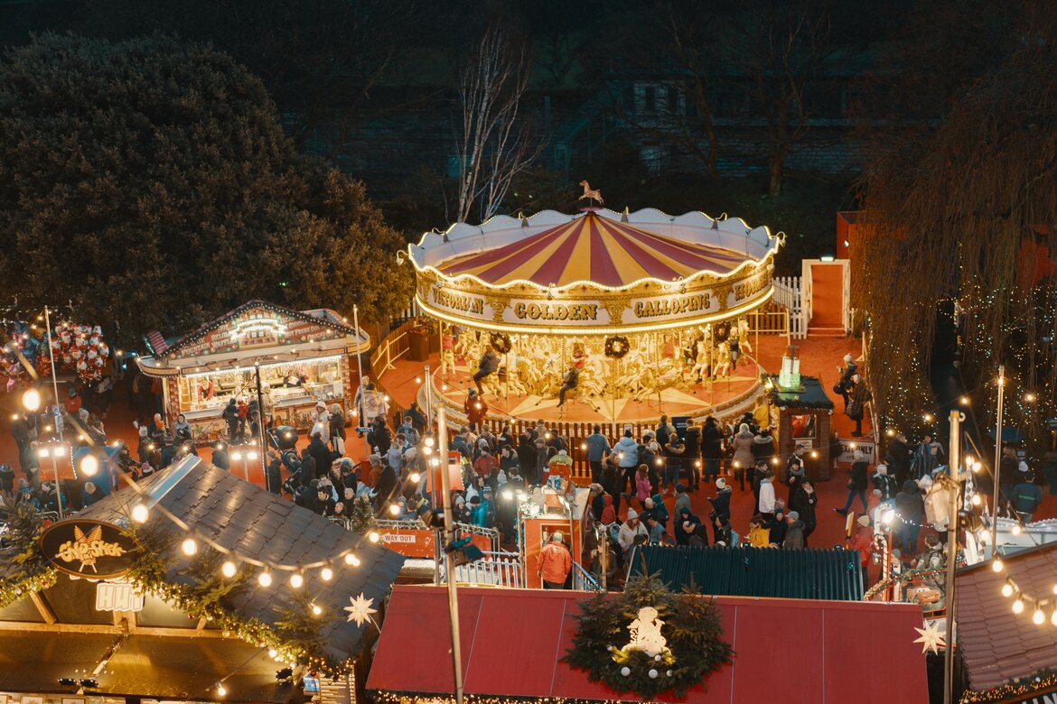 Christmas Carousel in Edinburgh - A brightly lit carousel twinkling in the night, with throngs of people around. (© Ross Sneddon @ Unsplash)