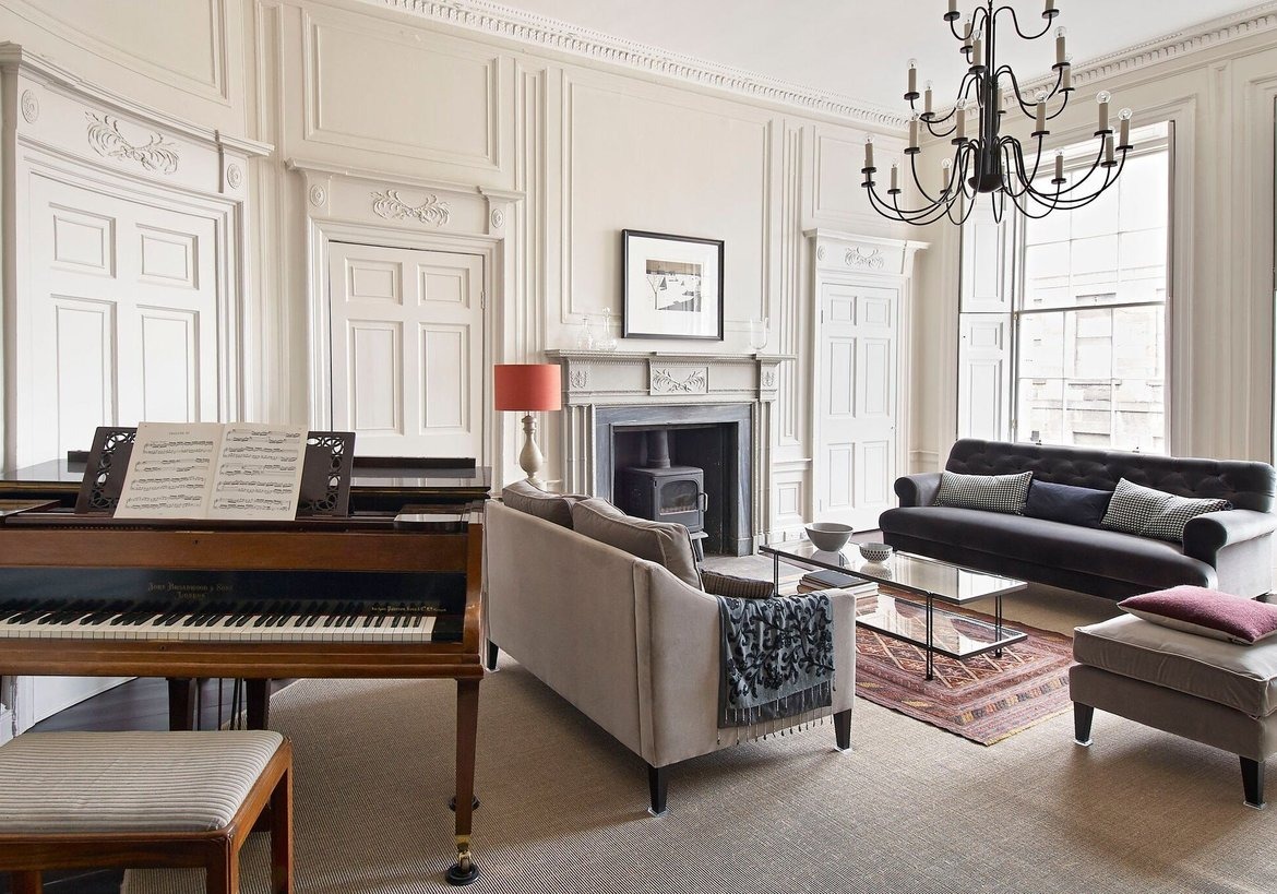 Private space in luxury holiday homes - A light coloured spacious room with elegant furniture and a piano in the foreground.