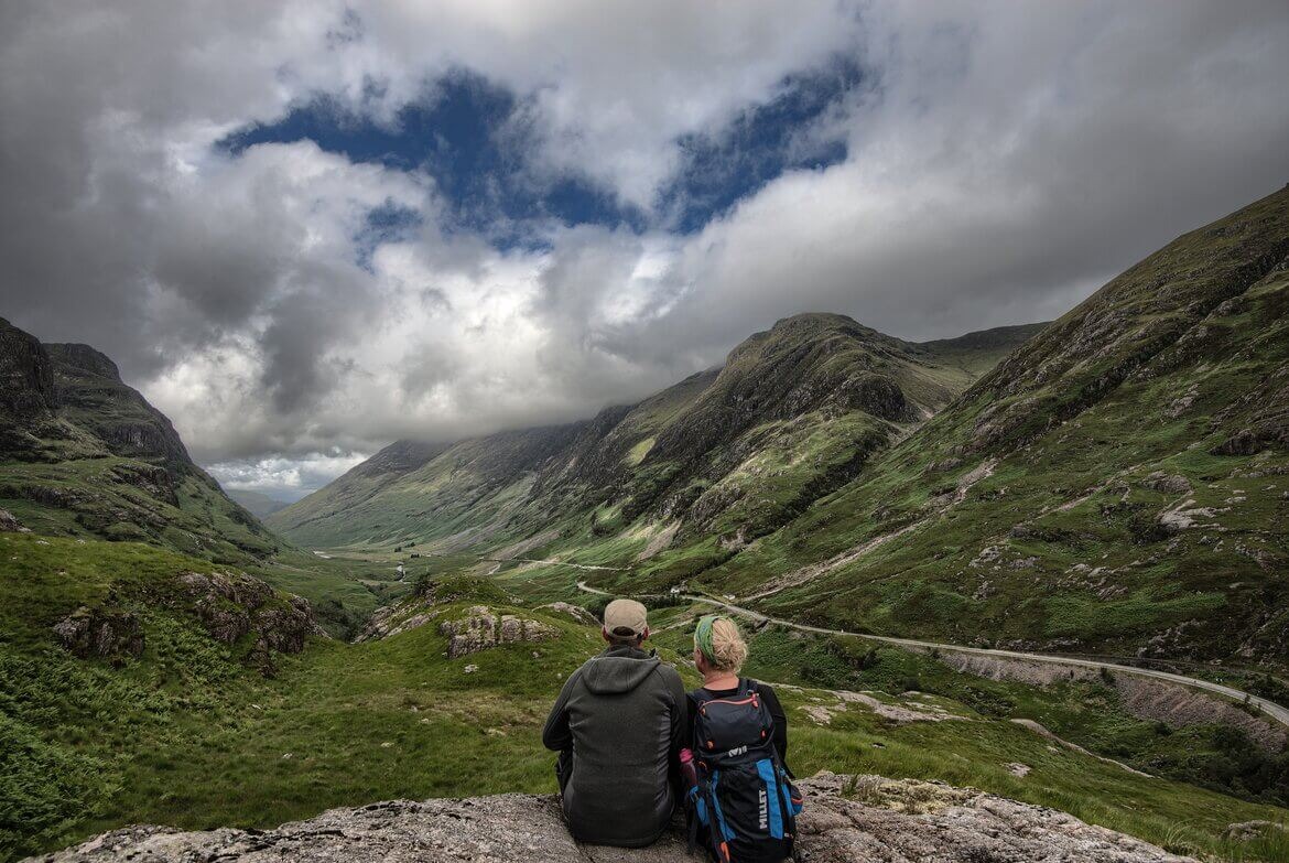 Hiking in Scotland - Hikers enjoying the views over a green valley in Scotland