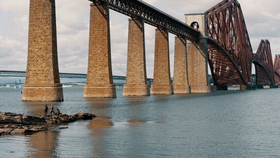 The Forth Bridge in South Queensferry - A majestic red rail bridge spanning a river. (© Ross Sneddon on Unsplash)
