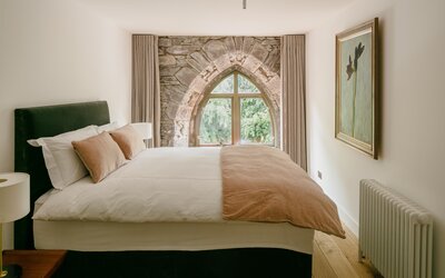 Bedroom in a Vacation Rental in Scotland - Main bedroom with vintage window opening to view of greenery.