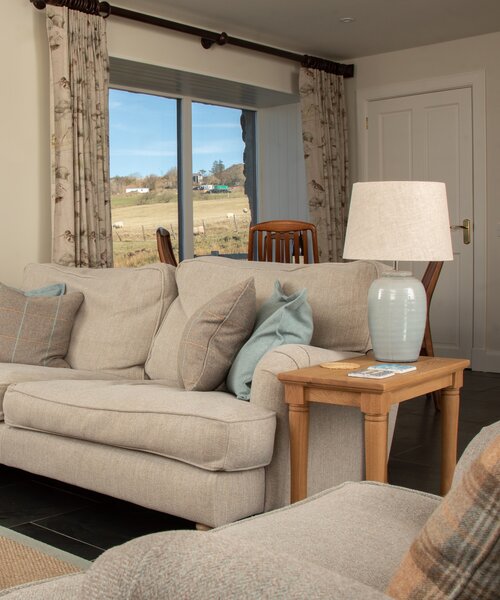 Cosy Lounge with High Speed Internet in Scotland - Well-lit lounge area with sumptuous seating and chic décor, featuring a picture window that frames the tranquil hills of the Isle of Skye