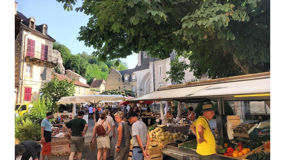 Marché de Montignac-Lascaux dans le Sud-Ouest de la France - Jour de marché en France, un marchand sert les touristes à l'ombre d'un grand tilleul. (© Voila Villas France)