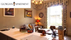 Case Study for The Georgian Apartment - View from the kitchen island to the dining room area with tall traditional windows and a sofa. Case Study for The Georgian Apartment - View from the kitchen island to the dining room area with tall traditional windows and a sofa.