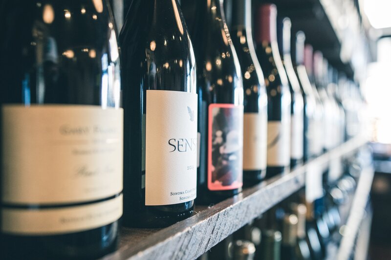 Wine bottles on a shelf - Wine bottles lined up on a shop shelf (© Scott Warman on Unsplash) Wine bottles on a shelf - Wine bottles lined up on a shop shelf (© Scott Warman on Unsplash)