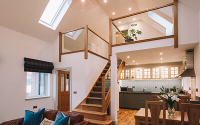 Spacious luxurious living space in a modern cottage - Sitting and dining area with fully equipped kitchen and the stairs up to the mezzanine where there’s a desk for work area or a place to quietly read