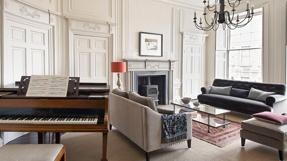 Lounge Area in a Self-Catered Apartment - Stylish lounge area featuring comfortable sofas and a piano, to unwind after a long day in the city of Edinburgh