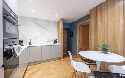 Dining Table - A fully equipped, open-plan kitchen with a clean, contemporary design. It includes modern appliances, a sleek cabinetry and a dining area, seamlessly integrated into the open-plan living space.