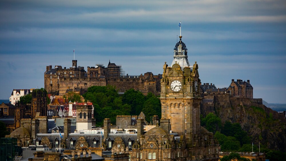 Edinburgh Castle - The background shows a wide blue river, with city scape focusing on a castle perched on a volcanic plug. (© Forever Edinburgh)