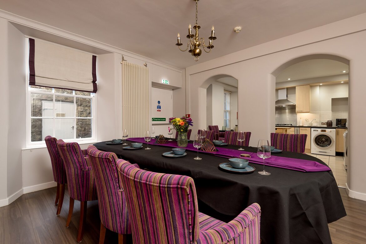 Group Dining Suite in a Holiday Rental - An expansive dining room designed for entertaining, featuring a banquet table and an arched view into a fully equipped adjoining kitchen