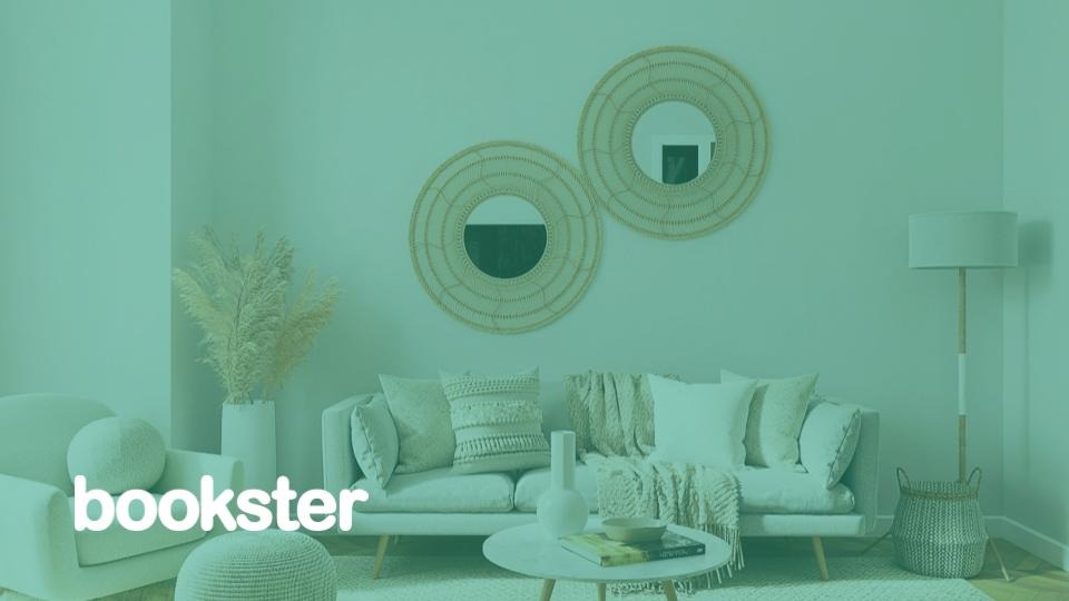 Holiday let management software - A scene from a light and airy living room with sofa and two round mirrors and a Bookster logo.
