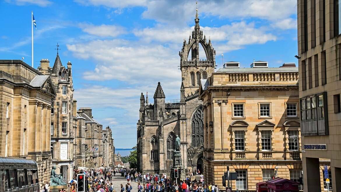 Visit Edinburgh streets during April 2027 - View down old Edinburgh streets, with a church on the right and people milling in the streets. Visit Edinburgh streets during April 2027 - View down old Edinburgh streets, with a church on the right and people milling in the streets.